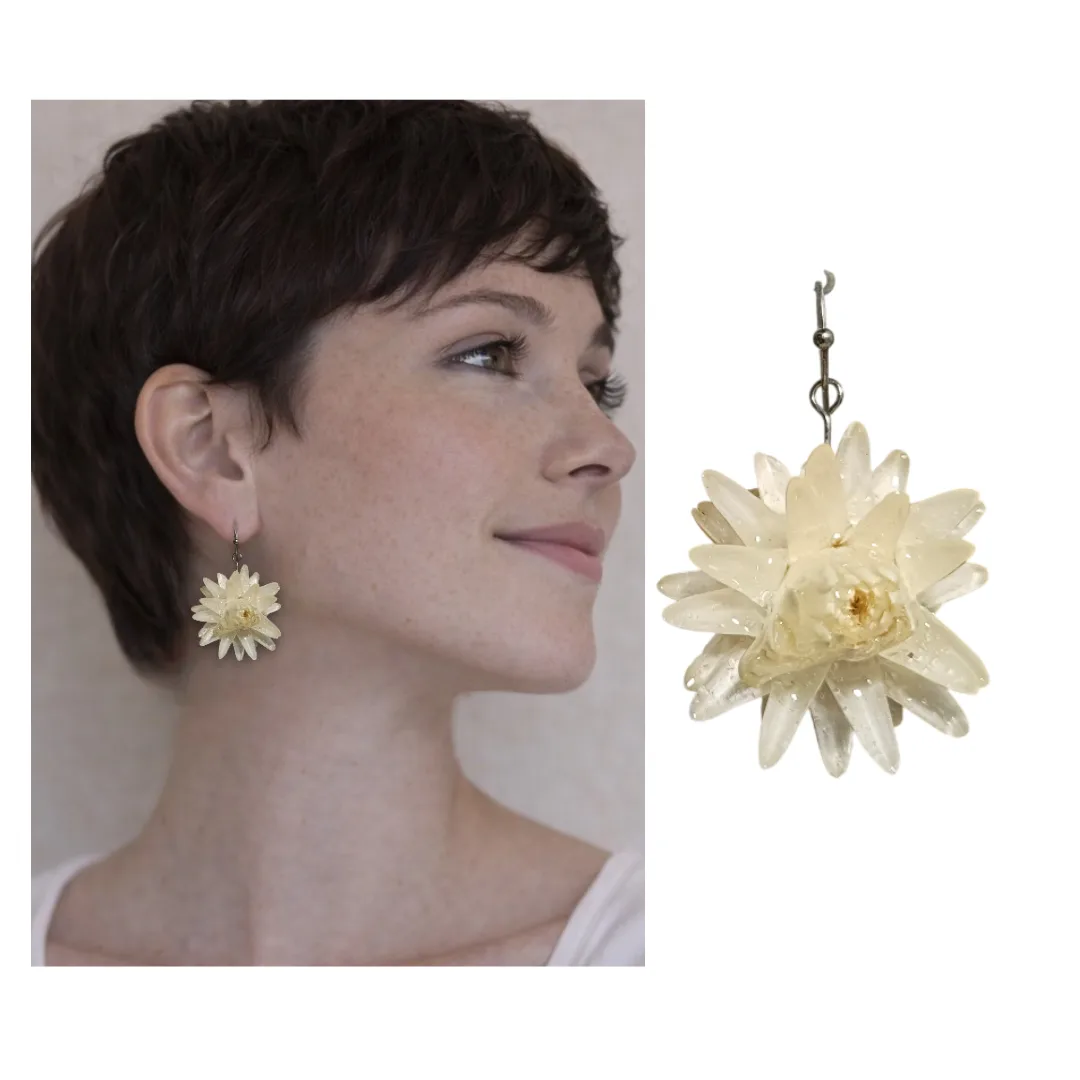 Model in profile with short dark hair wearing handmade white natural flower earring in crystal resin, with enlarged earring at the side.