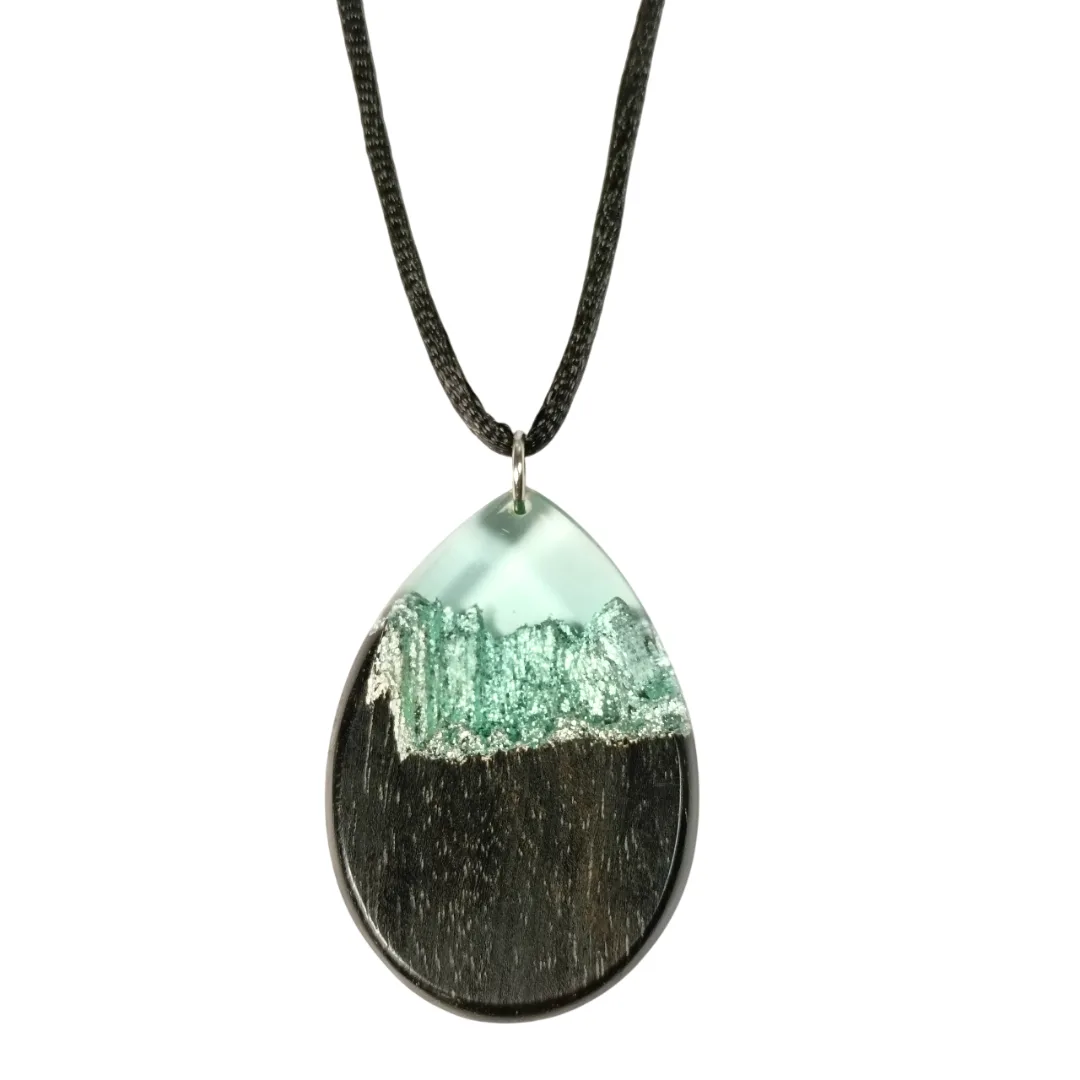 Close-up do pendente gota em ébano com resina azul clara transparente e reflexos prateados em relevo tipo skyline