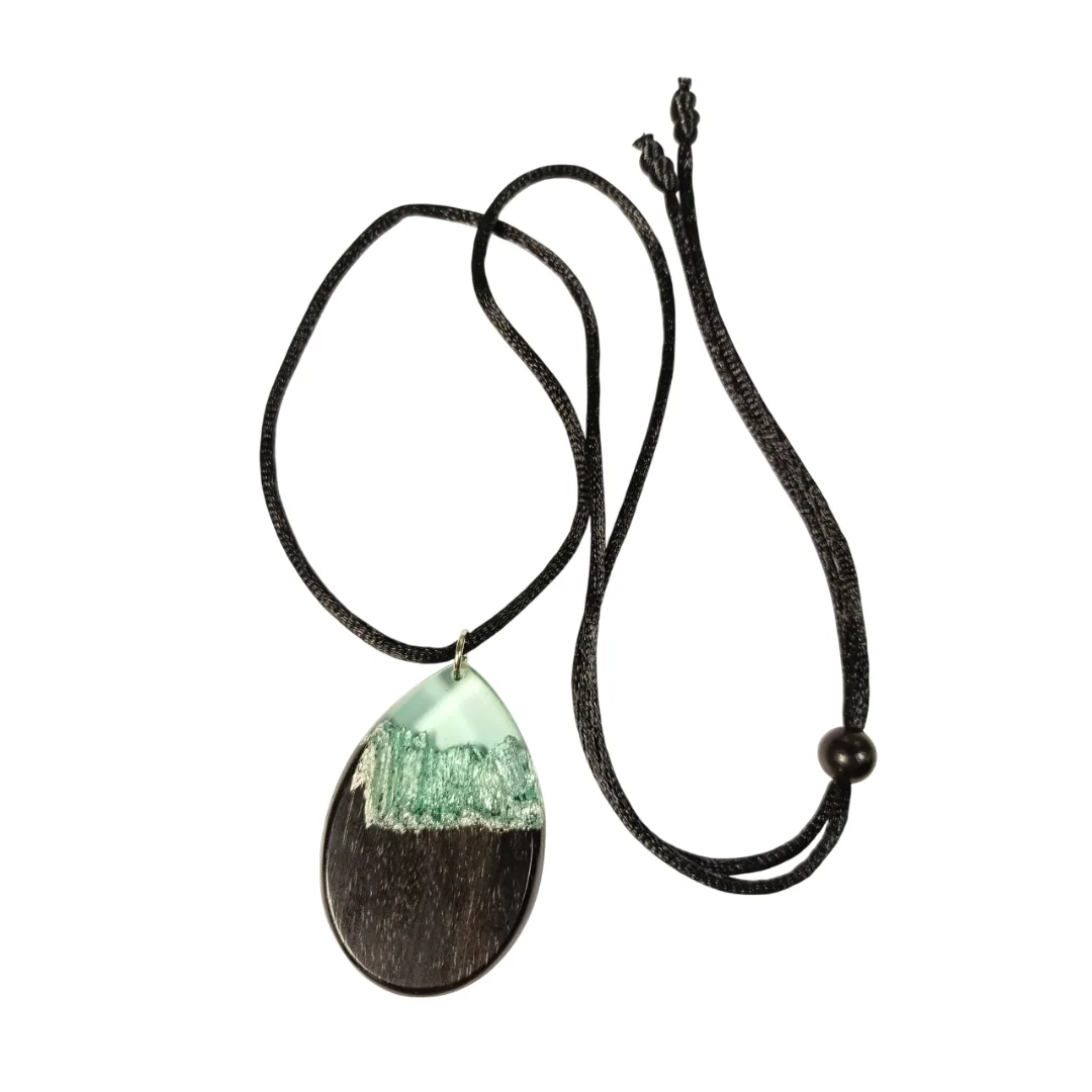 Pendente em forma de gota em madeira de ébano e resina azul clara transparente com reflexos prateados, no cordão preto