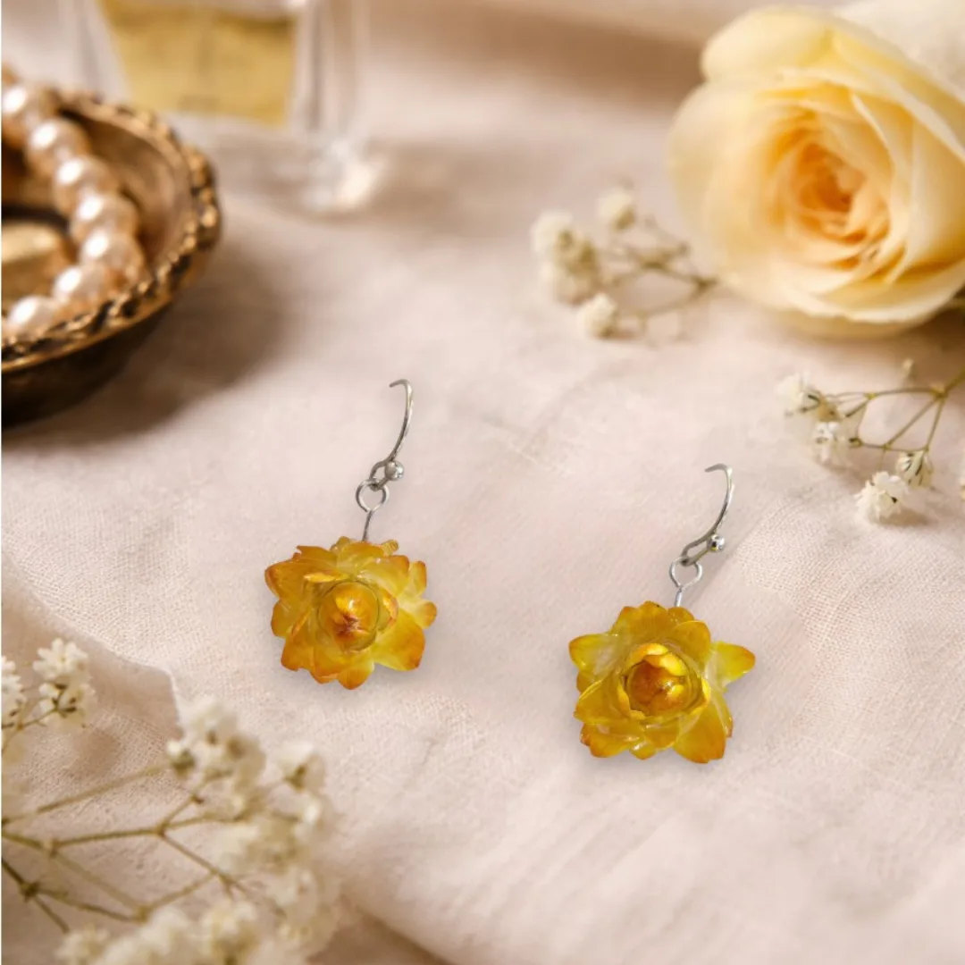 Brincos Beijo de Sol com flor natural amarela em resina em cenário romântico e delicado