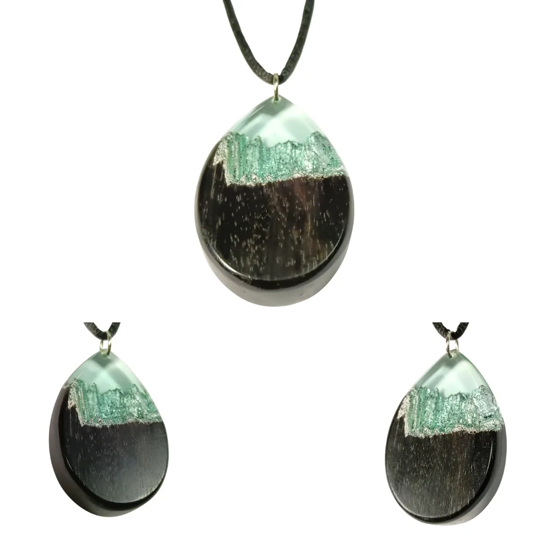 Pendente em forma de gota em madeira de ébano e resina azul clara transparente com reflexos prateados, no cordão preto