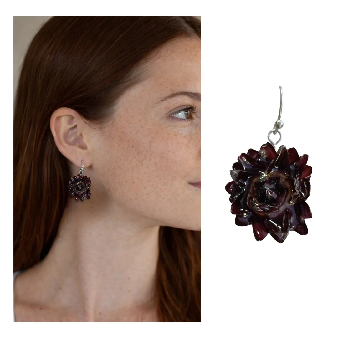 Modelo em perfil a usar brinco artesanal com flor natural Bordeaux em resina; detalhe ampliado do brinco em destaque.