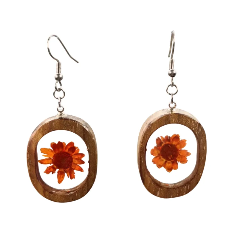 Par de brincos artesanais em madeira de acácia com flor laranja encapsulada em resina, pendente oval com gancho prateado.