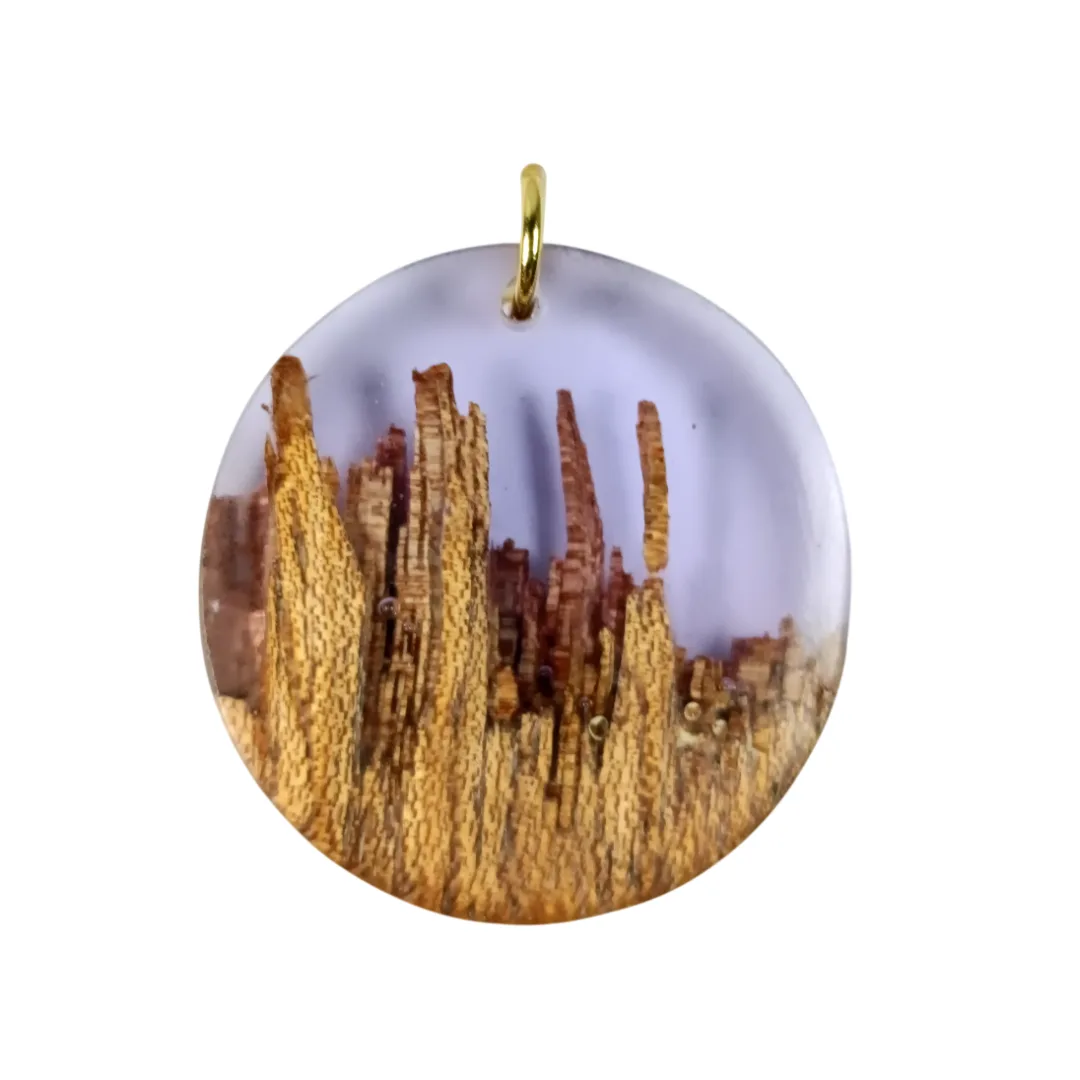 Round pendant in acacia wood and translucent lilac resin, with gold ring, front view.