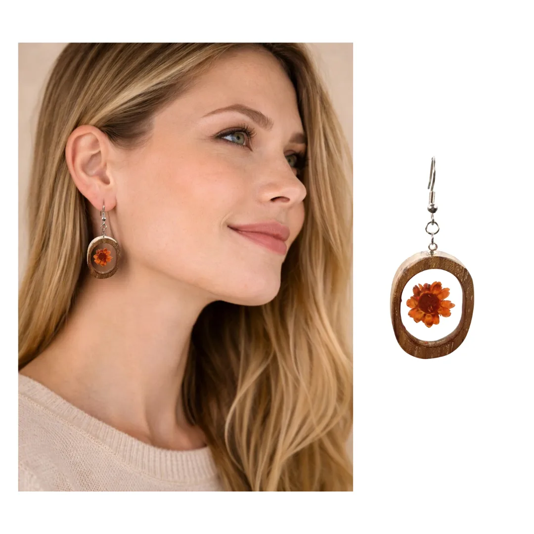 Modelo em perfil a usar brinco oval em madeira de acácia com flor laranja em resina; brinco ampliado em destaque ao lado.