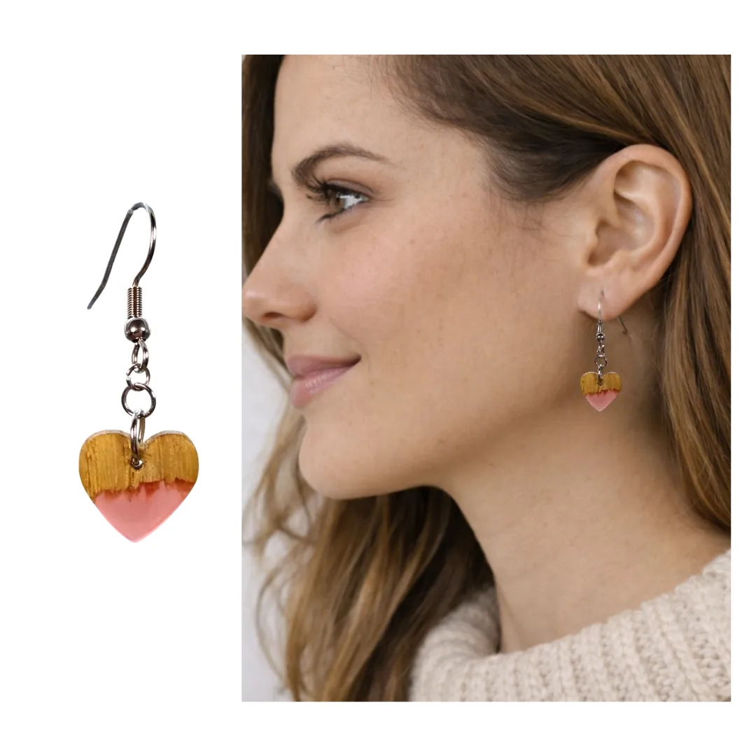 Brincos coração Cordis em madeira e resina rosa vistos ao ouvido em foto de modelo