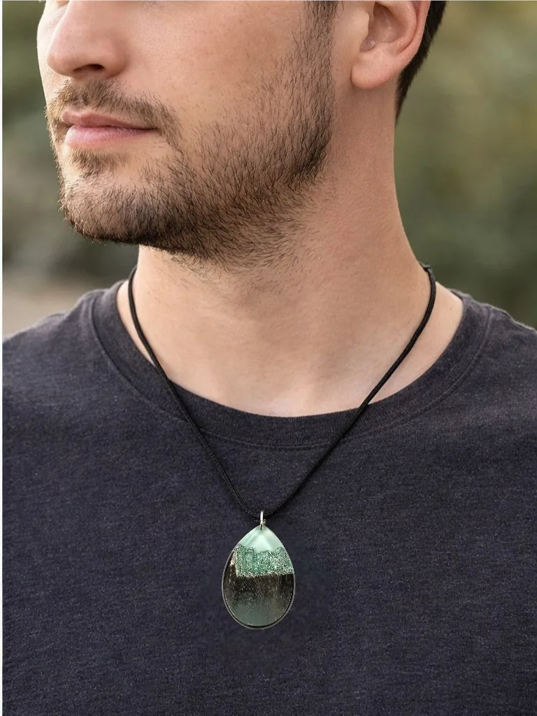 Modelo feminina a usar colar com pendente em forma de gota, em madeira de ébano e resina azul translúcida com reflexos prateados, em fio preto.