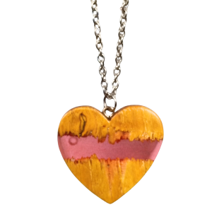 Close-up do pendente coração em castanho com faixa de resina rosa, acabamento artesanal